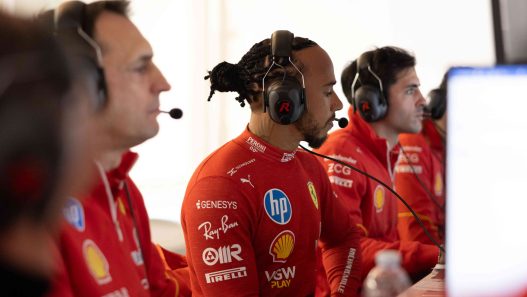 Lewis Hamilton in a headset with Ferrari engineers in the garage at Fiorano