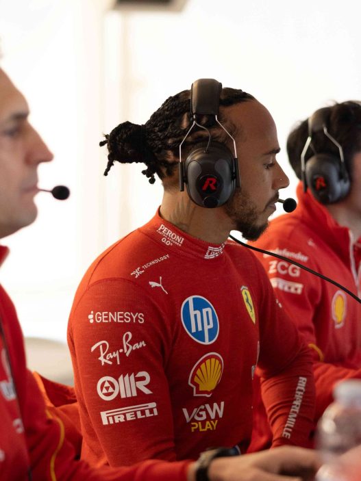 Lewis Hamilton in a headset with Ferrari engineers in the garage at Fiorano