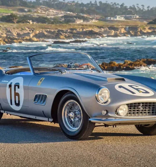 The silver 1959 Ferrari 250 GT LWB California Spider Competizione by the coast