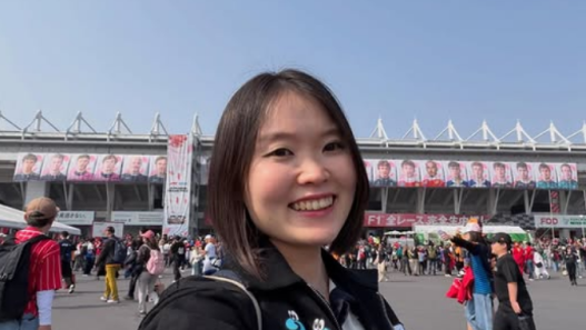 Mizuki smiling for a selfie at a Formula 1 circuit
