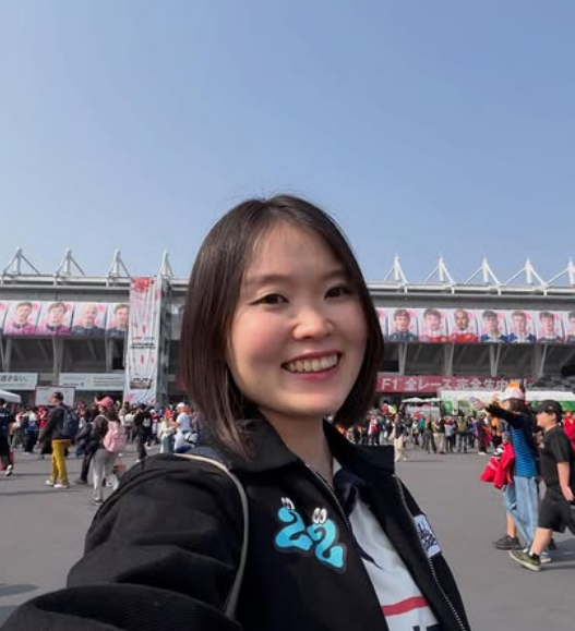 Mizuki smiling for a selfie at a Formula 1 circuit
