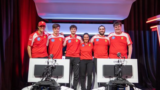 The Scuderia Ferrari HP Esports team standing on stage behind their racing simulators