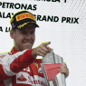 Sebastian Vettel in Ferrari kit smiling and pointing on the Malaysian Grand Prix podium at Sepang