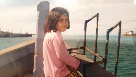 A woman sitting on the deck of a boat looking out over the sea