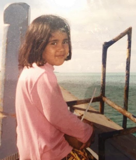 A woman sitting on the deck of a boat looking out over the sea
