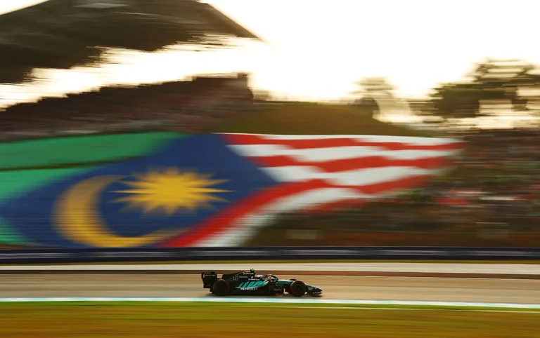 A Mercedes speeding past a blurred Malaysian flag at Sepang