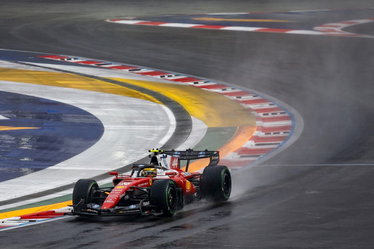 A Ferrari kicking up spray on a wet track at Marina Bay