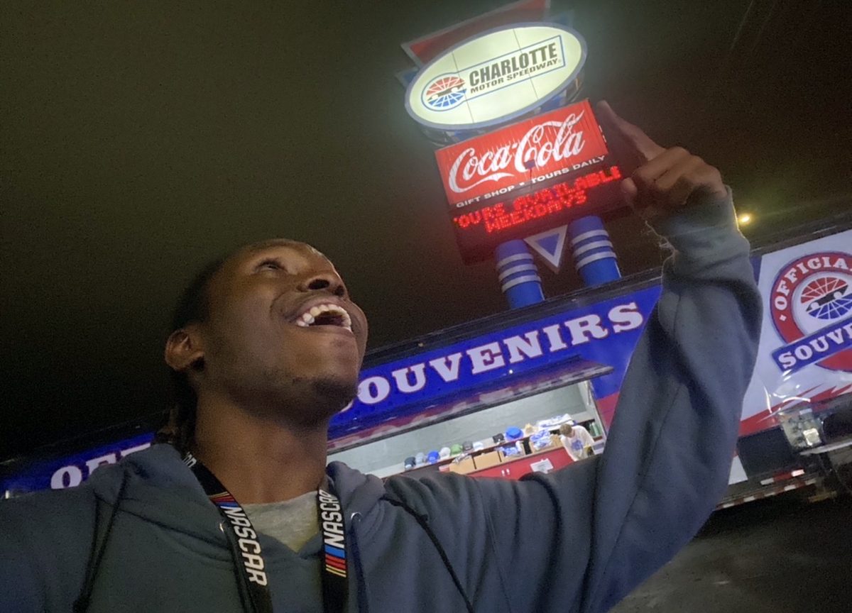 1NTERN grinning beneath the Charlotte Motor Speedway sign at night