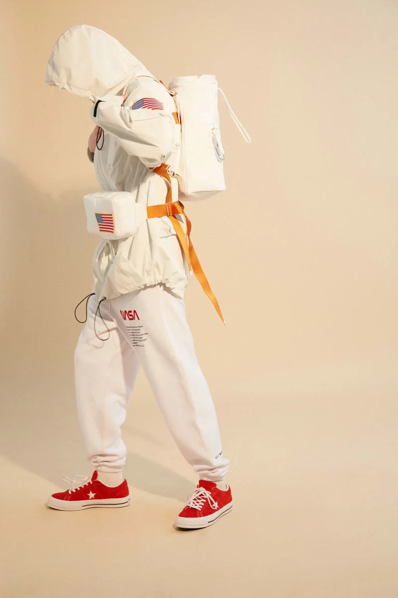 A model in a white NASA look with an orange harness and a white backpack, from the Fall/Winter 2018 lookbook