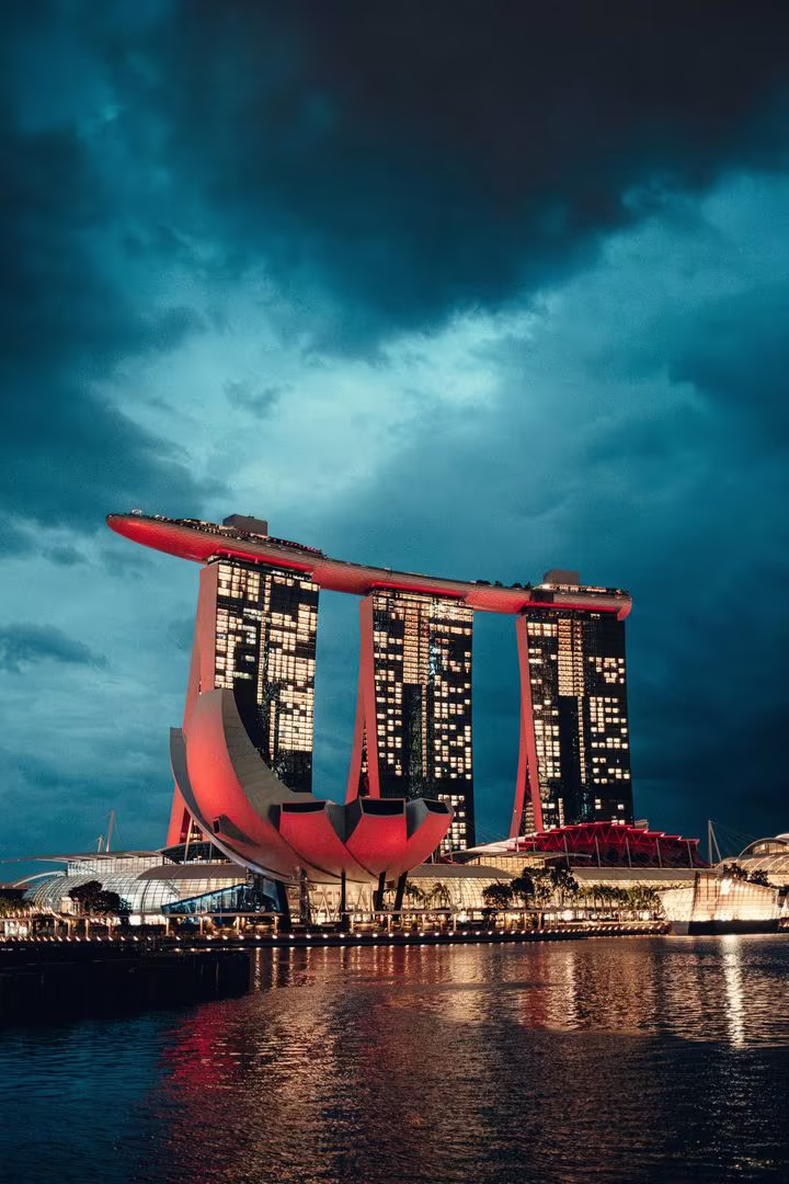 Marina Bay Sands and the ArtScience Museum lit up at dusk under heavy clouds