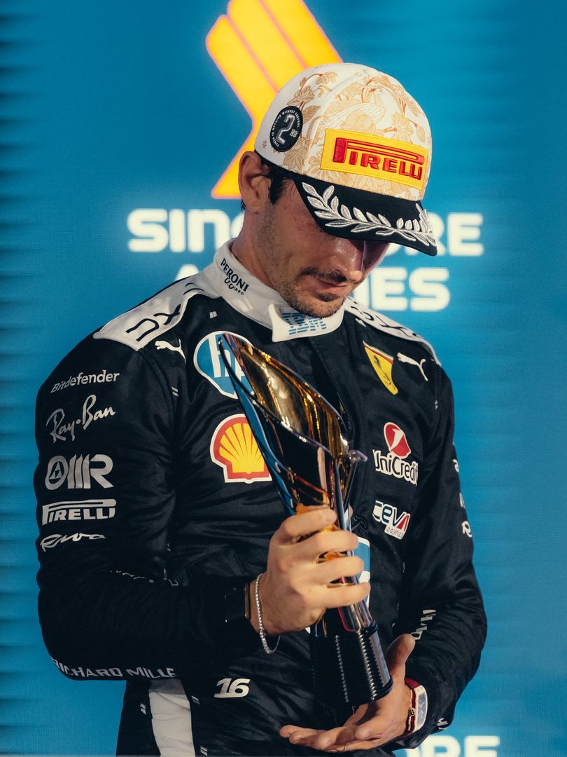 Charles Leclerc looking down at his second-place trophy on the podium