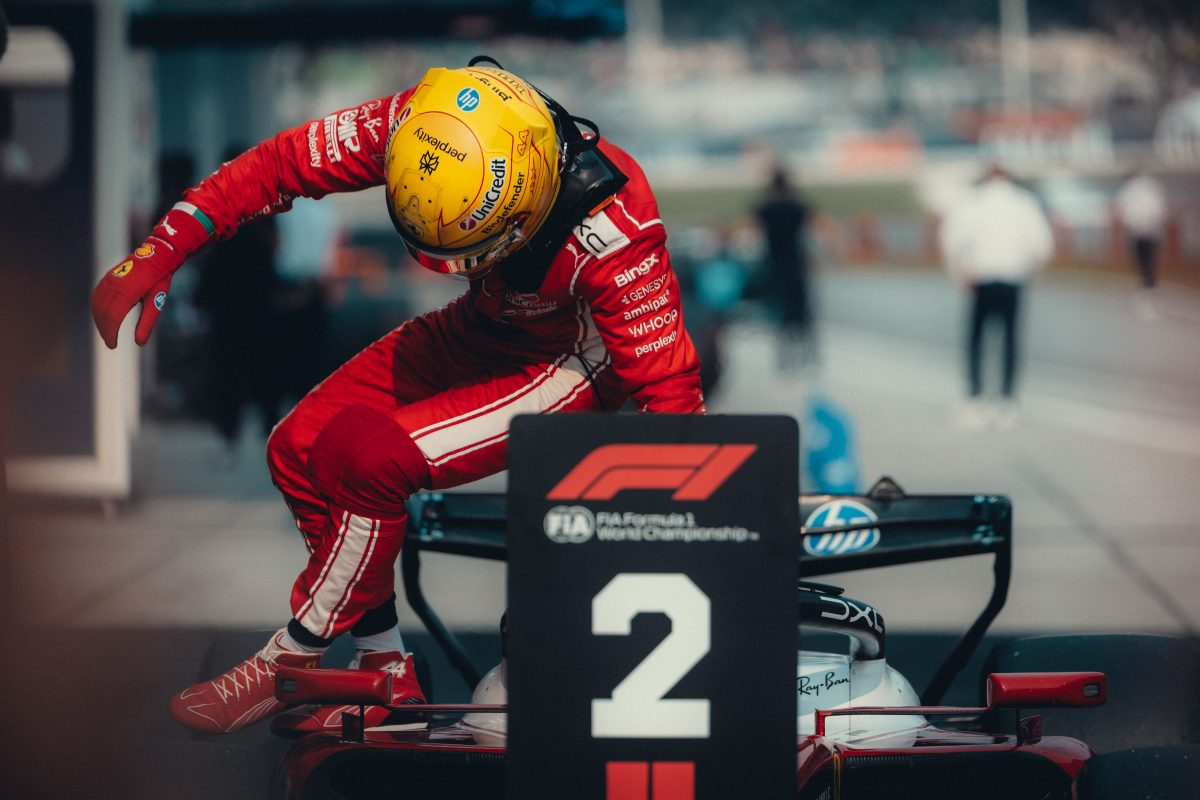 Lewis Hamilton climbing out of his Ferrari behind the P2 board in parc ferme