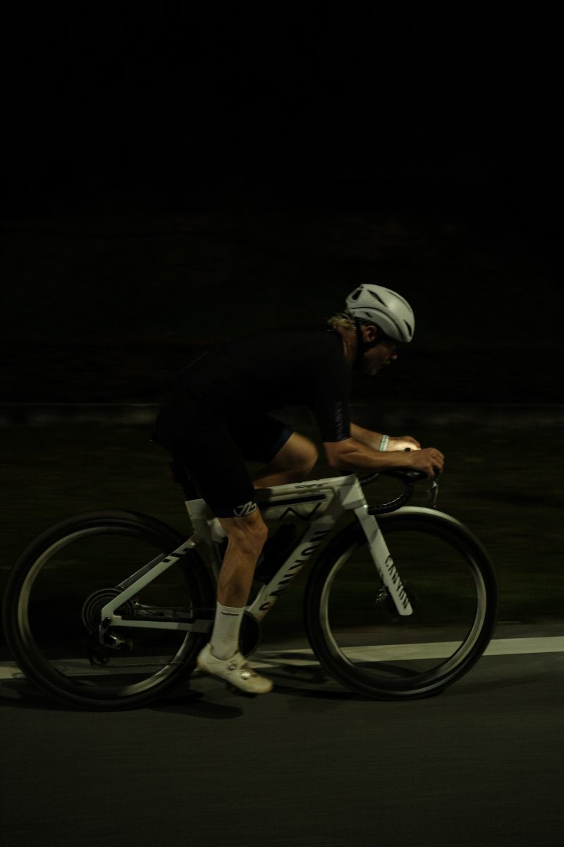 Valtteri Bottas riding a white road bike along a dark road at night