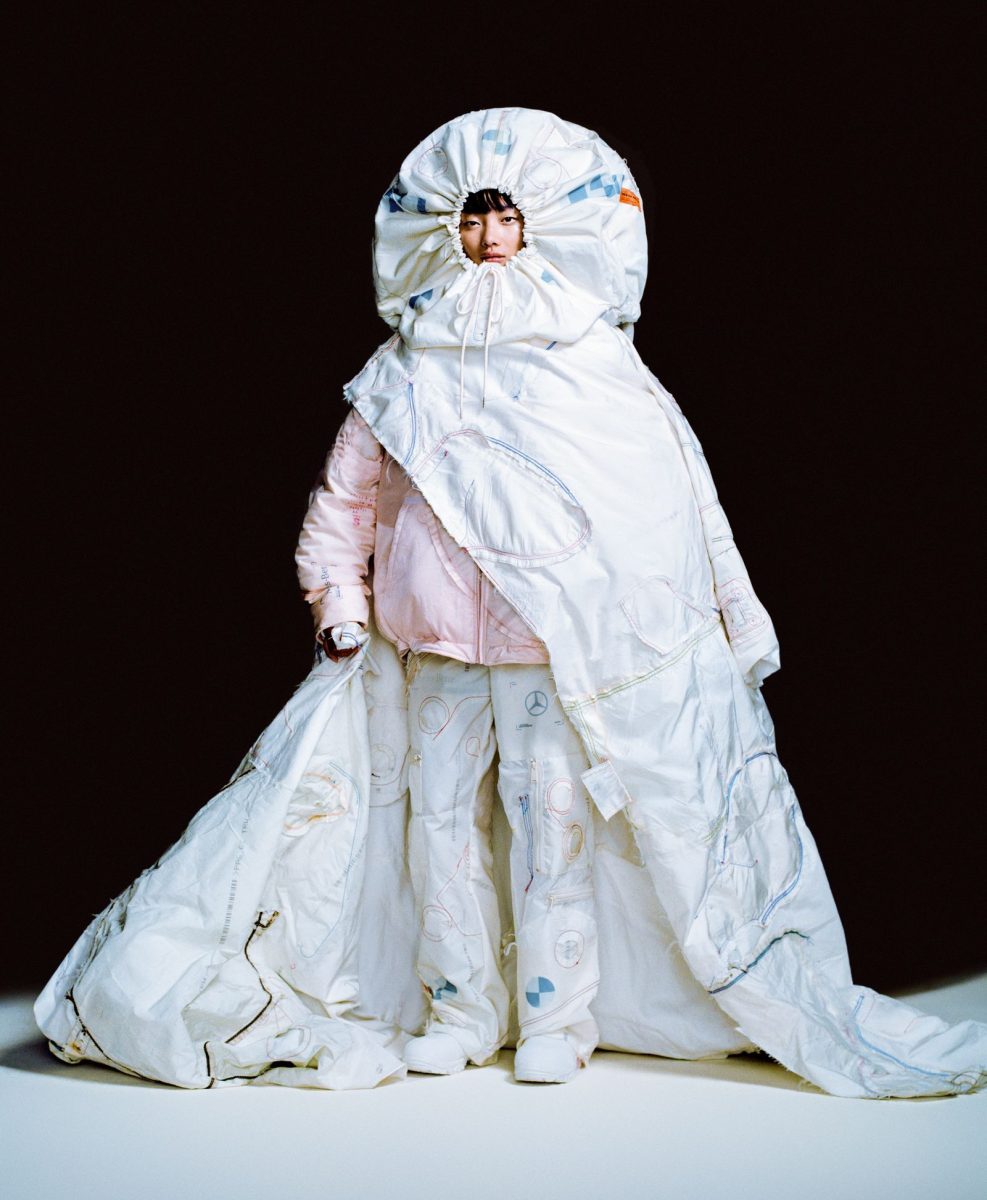 A model in a voluminous white airbag-material gown and hood with a pink layer underneath