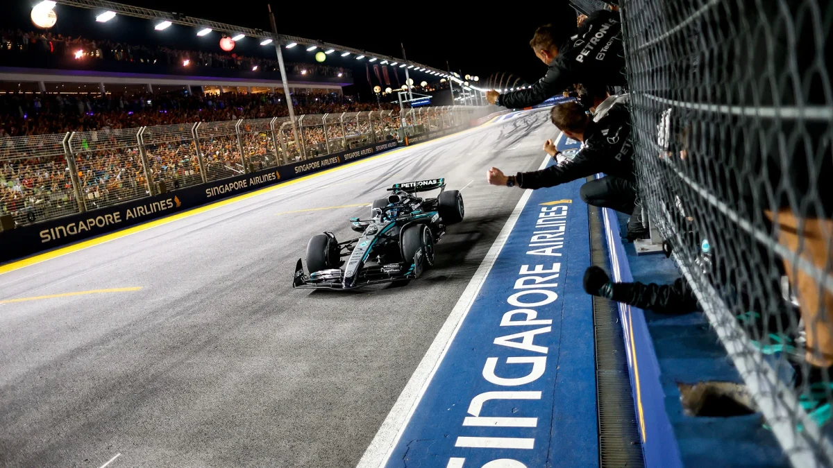 Mercedes team members cheering from the pit wall fence as a Mercedes crosses the line at Marina Bay