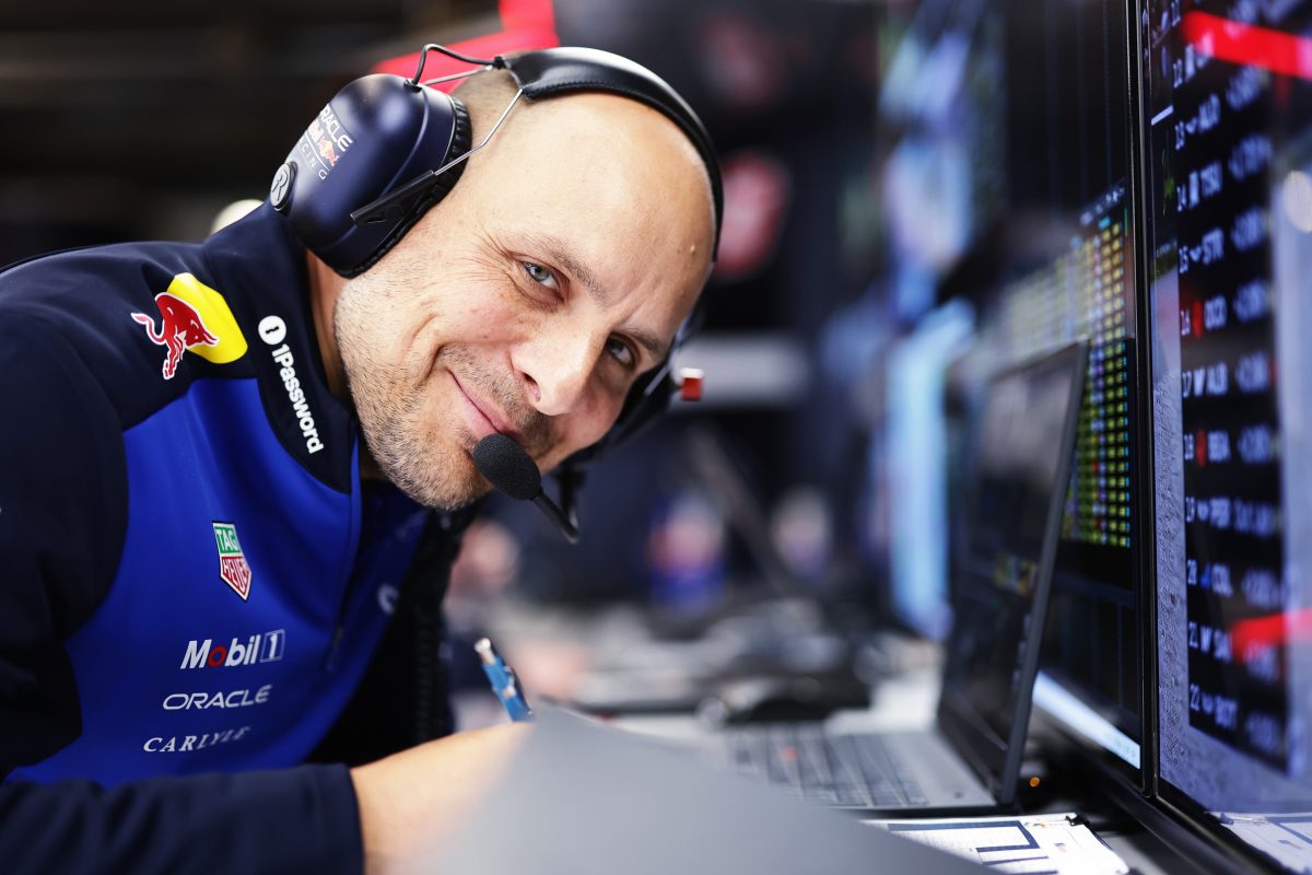 Gianpiero Lambiase smiling in his headset at the Red Bull garage desk