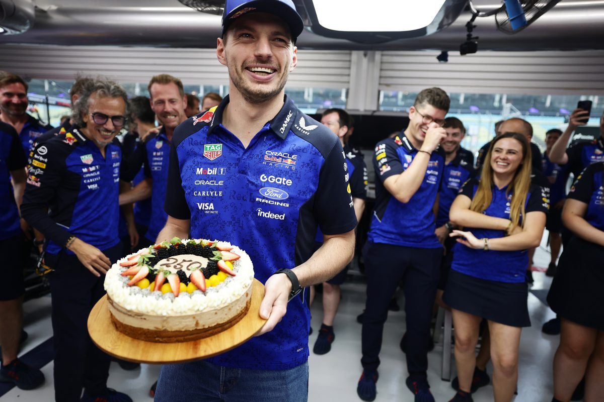 Max Verstappen holding a cake with Red Bull team members for his 250th Grand Prix