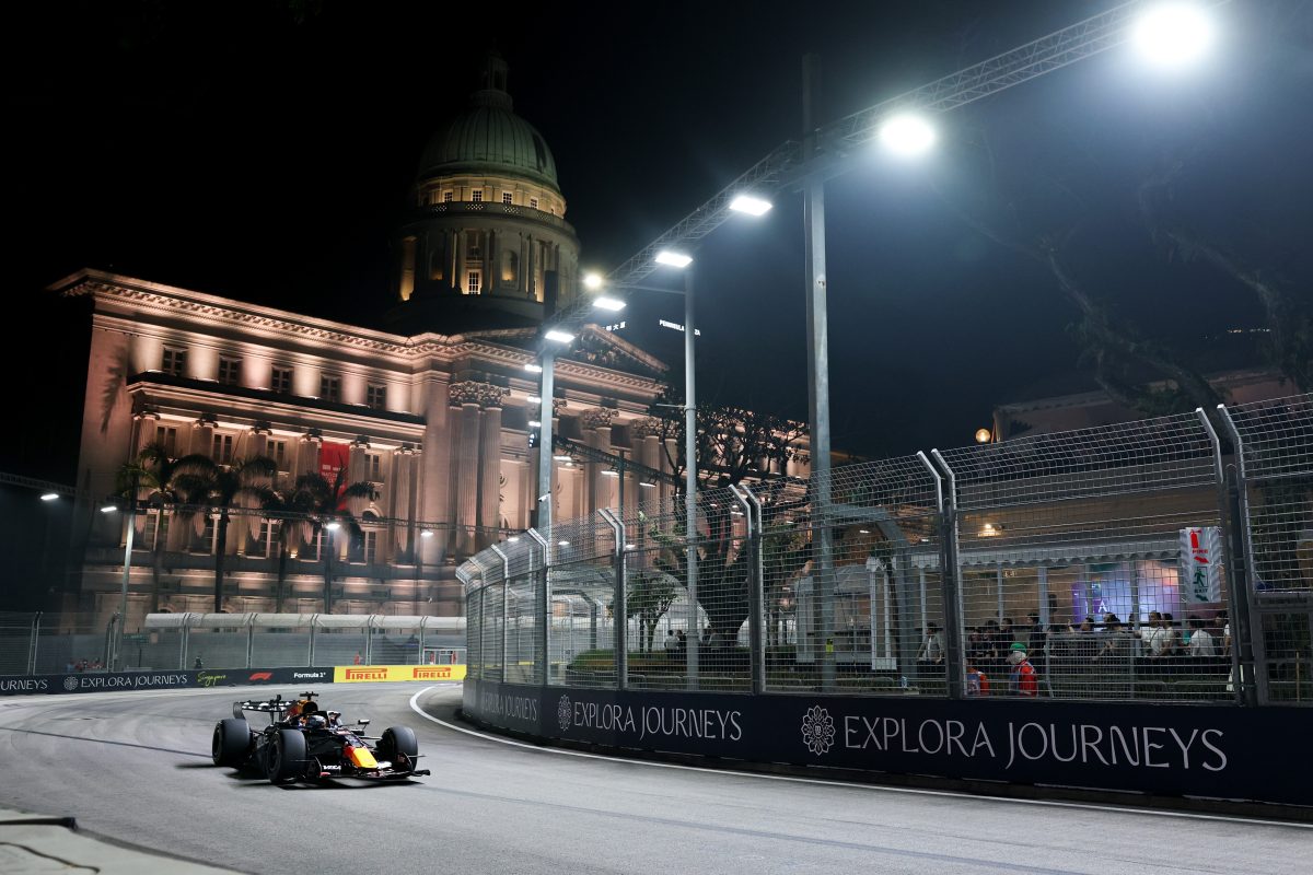 Max Verstappen’s Red Bull on track at night, passing a floodlit domed building at Marina Bay