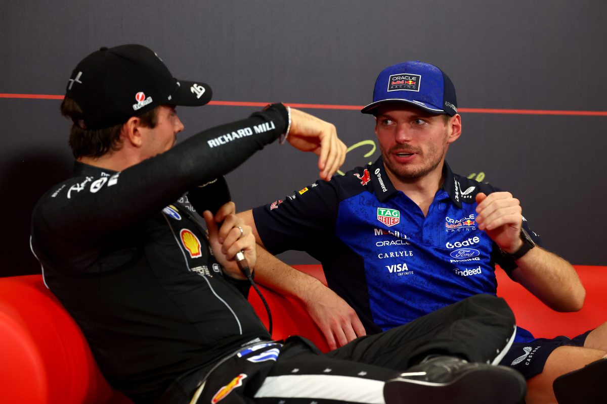 Charles Leclerc and Max Verstappen talking side by side on a red sofa in the press conference