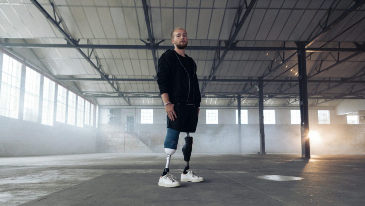 Billy Monger standing in an empty warehouse on his prosthetic legs