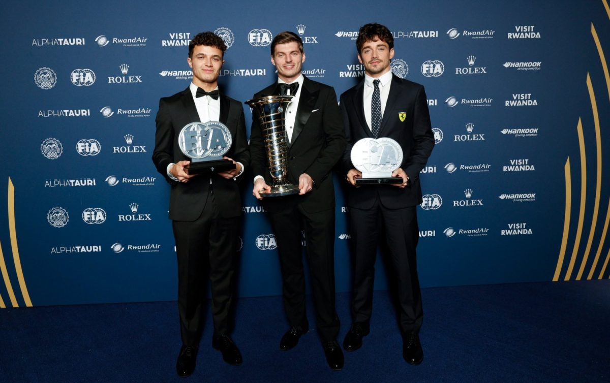 Lando Norris, Max Verstappen and Charles Leclerc holding trophies in front of a Visit Rwanda backdrop