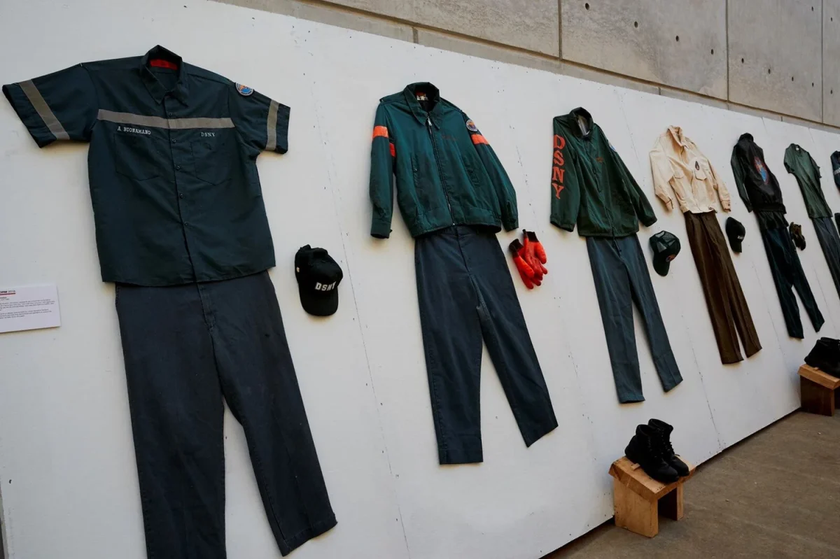 Upcycled DSNY uniforms from the UNIFORM collection pinned to a white wall